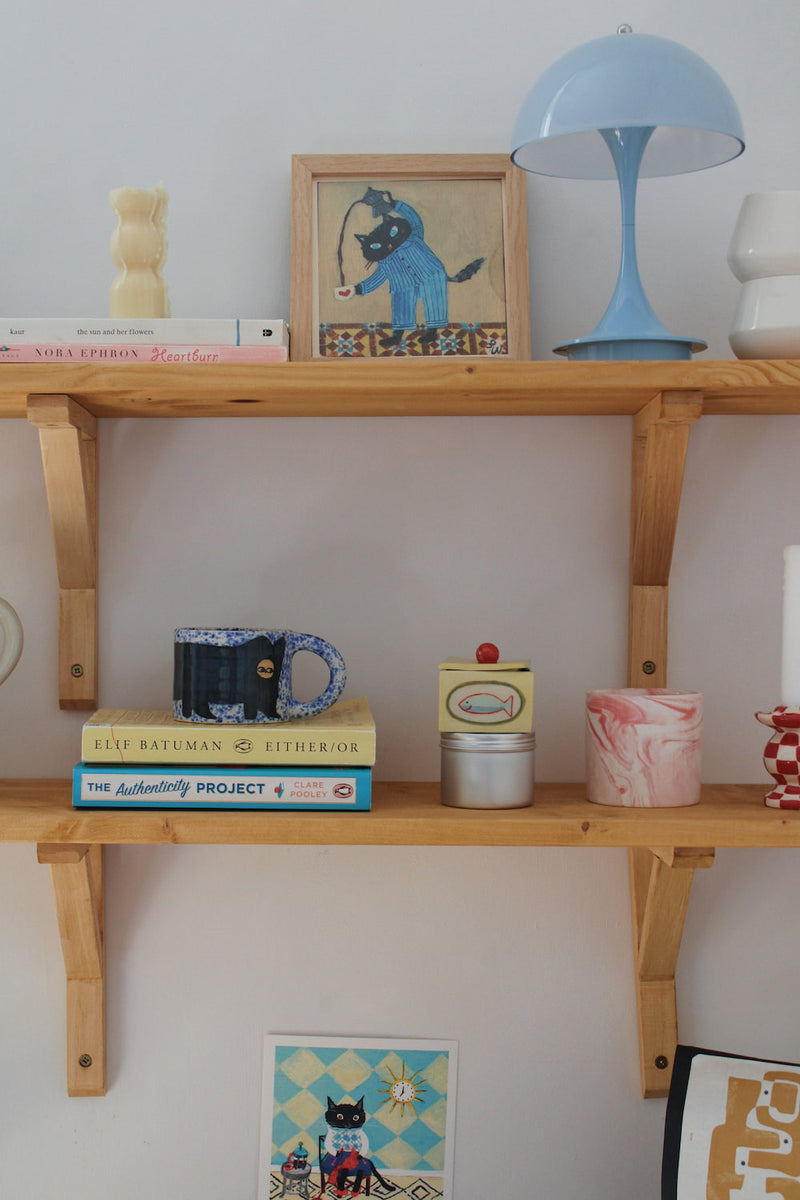 Cat’s Pyjamas Art Print by an independent artist, displayed in a wooden frame on a shelf with colourful home decor and ceramics.