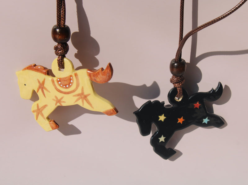 Pony charm necklaces with handmade ceramic horse pendants in amber yellow and midnight black on brown cord.