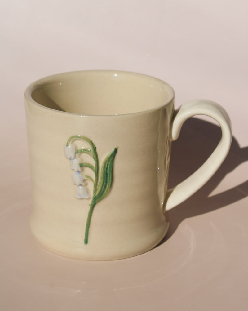 Bellis ceramic mug with lily of the valley motif, handmade floral coffee cup for cozy morning rituals.