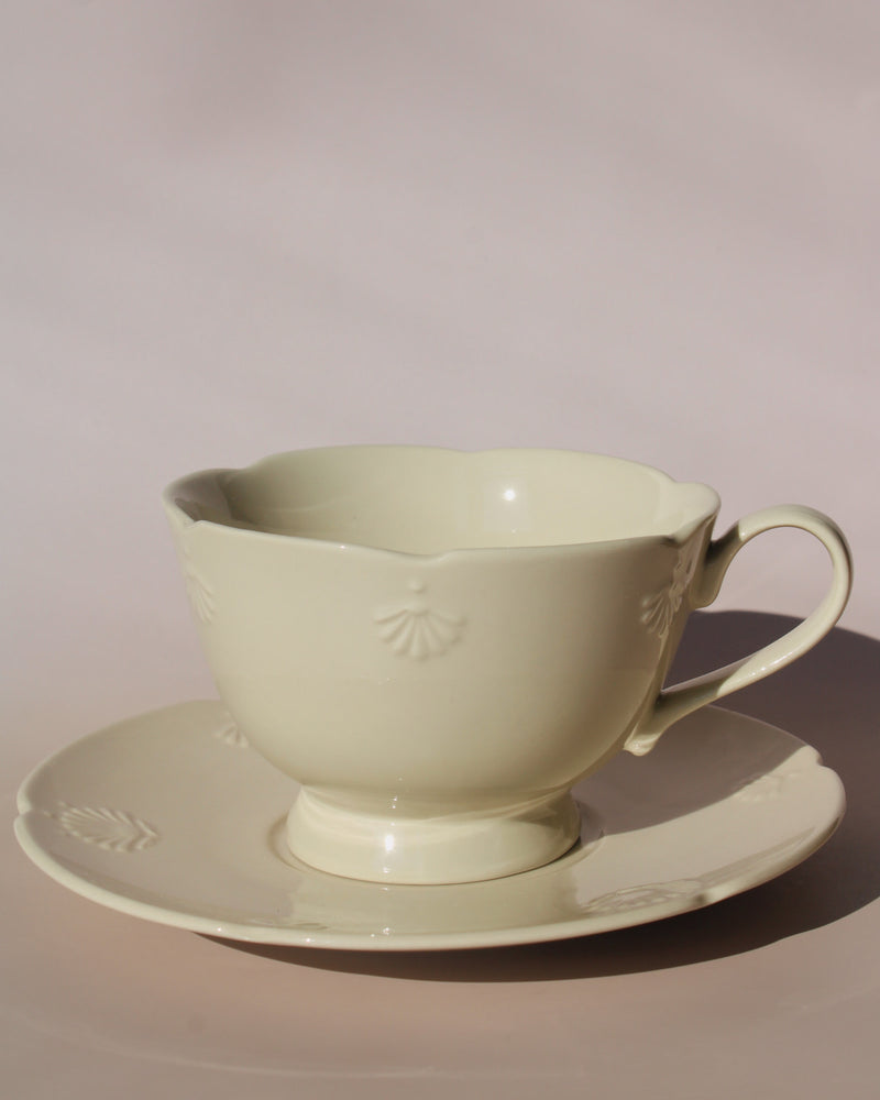 Handmade Sorelle ceramic cup and saucer set in soft cream glaze with delicate embossed shell details, elegant tea cup for coffee or afternoon tea.