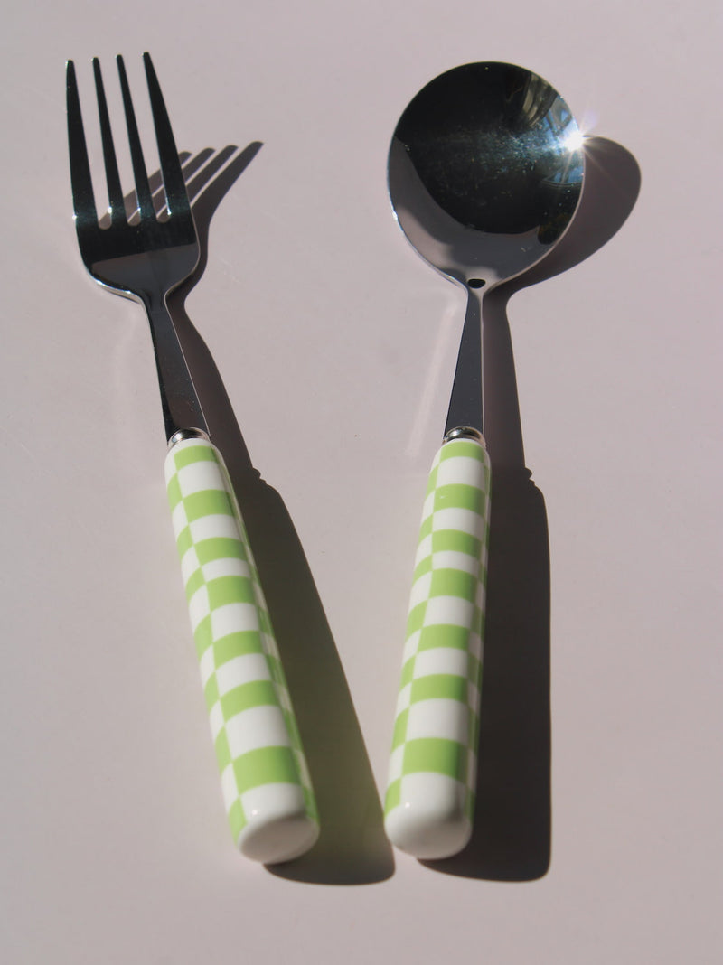 Nico Fork and Spoon Set in stainless steel with green and white checkered handles, on a soft pink background.