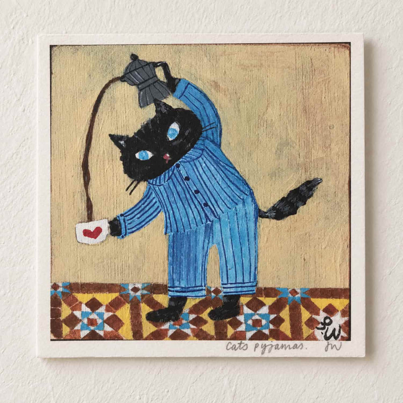 Cat’s Pyjamas Art Print featuring a black cat in blue striped pajamas making tea, with a patterned floor and warm beige background.