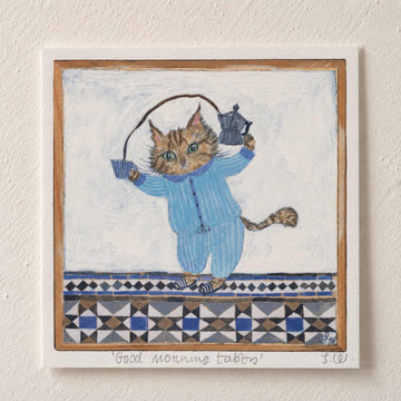 Good Morning Tabby Art Print featuring a tabby cat in blue striped pajamas holding a moka pot and coffee cup, set against a hand-painted blue and cream patterned background.