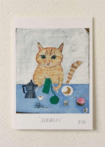 Marcel Cat Art Print featuring an orange tabby cat knitting green yarn at a blue table, surrounded by a moka pot, coffee cup, sewing supplies, scissors, and a small plate of pastries.