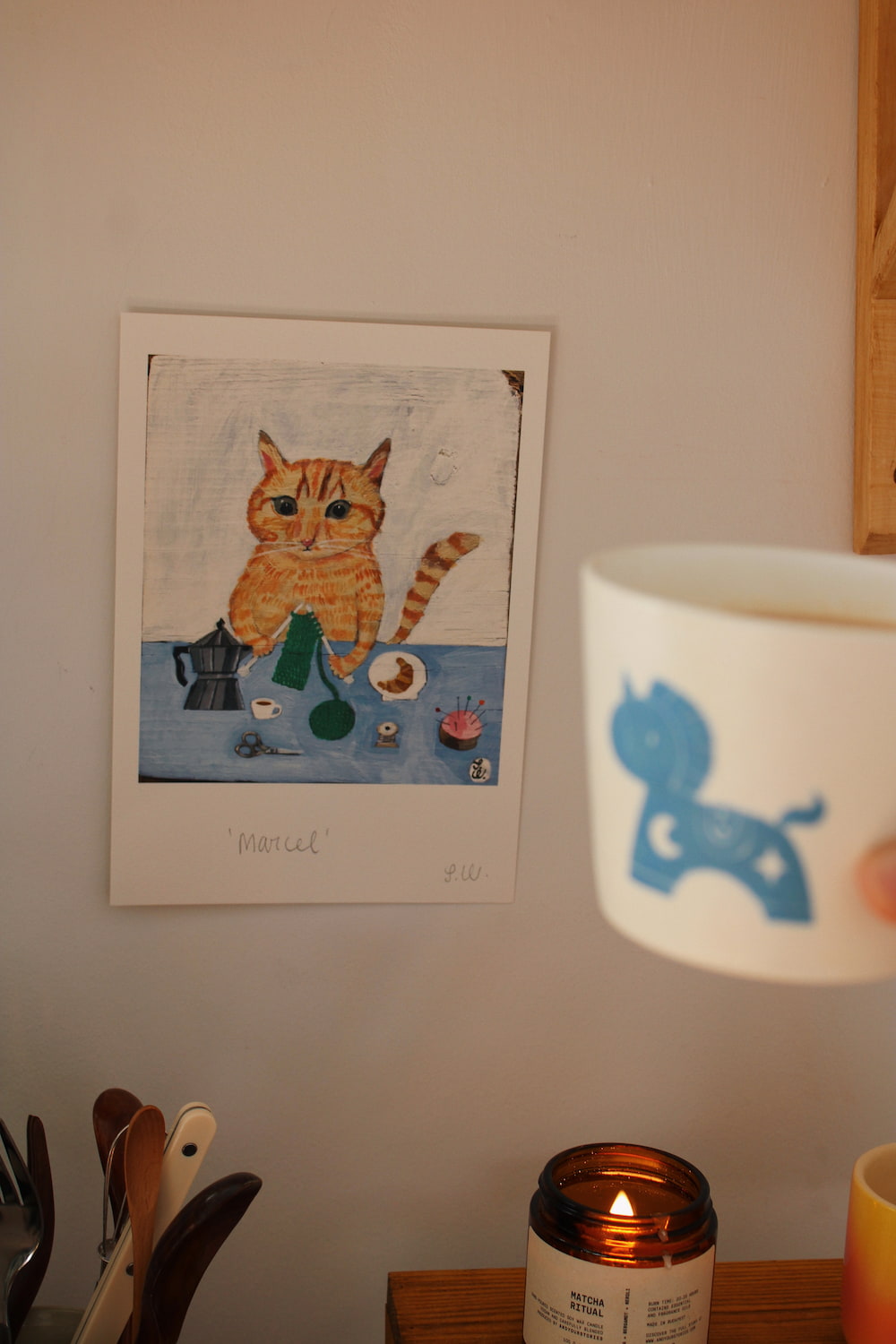 Marcel Cat Art Print – illustrated orange cat art print styled on a wall above a colourful coffee station with ceramic mugs, books and home accessories