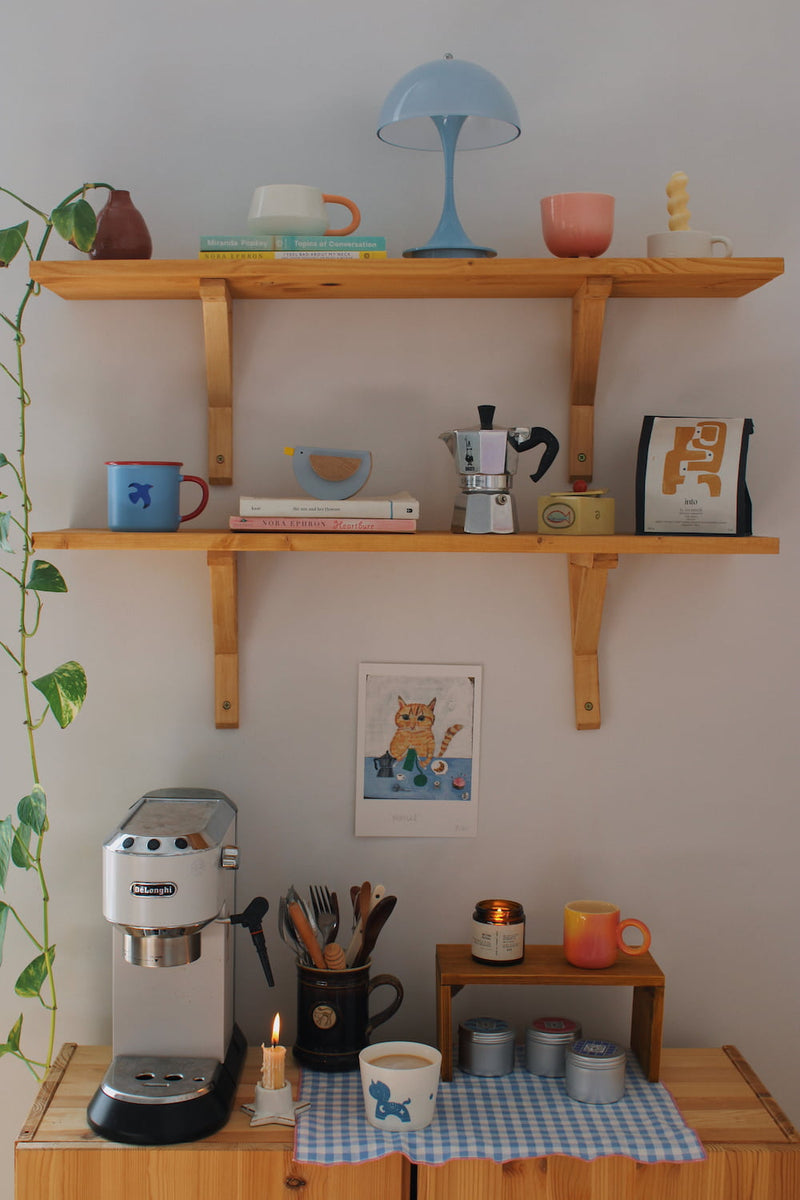 Marcel Cat Art Print – illustrated orange cat art print styled on a wall above a colourful coffee station with ceramic mugs, books and home accessories