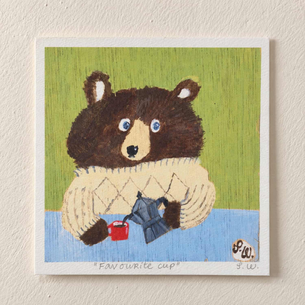 Favourite Cup Bear Art Print - A square art print featuring a whimsical illustration of a brown bear wearing a cream sweater and holding a blue coffee pot with a small red cup, set against a green and blue background. The print is mounted on a textured off-white wall.