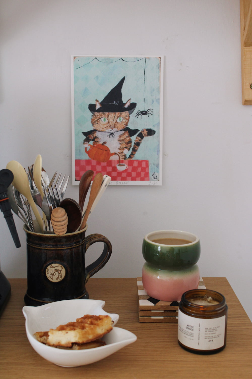 Witches Brew Cat Art Print – illustrated orange cat dressed as a witch with a pumpkin and spider, styled above a coffee station with colourful ceramics and a candle