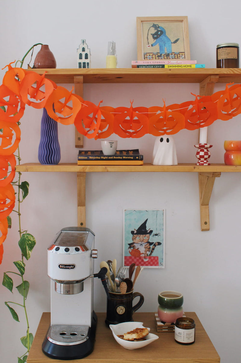 Witches Brew Cat Art Print – illustrated orange cat dressed as a witch with a pumpkin and spider, styled above a coffee station with colourful ceramics and a candle