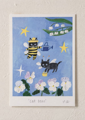 cat Bees Art Print featuring two playful black cats dressed as bees flying among flowers, stars, and lily of the valley blossoms against a blue background.