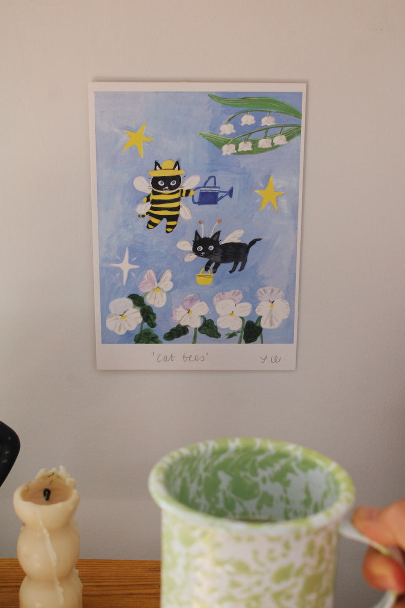 Cat Bees Art Print – illustrated art print featuring two black cats dressed as bees among flowers, styled above a coffee station with colourful ceramics and breakfast tableware