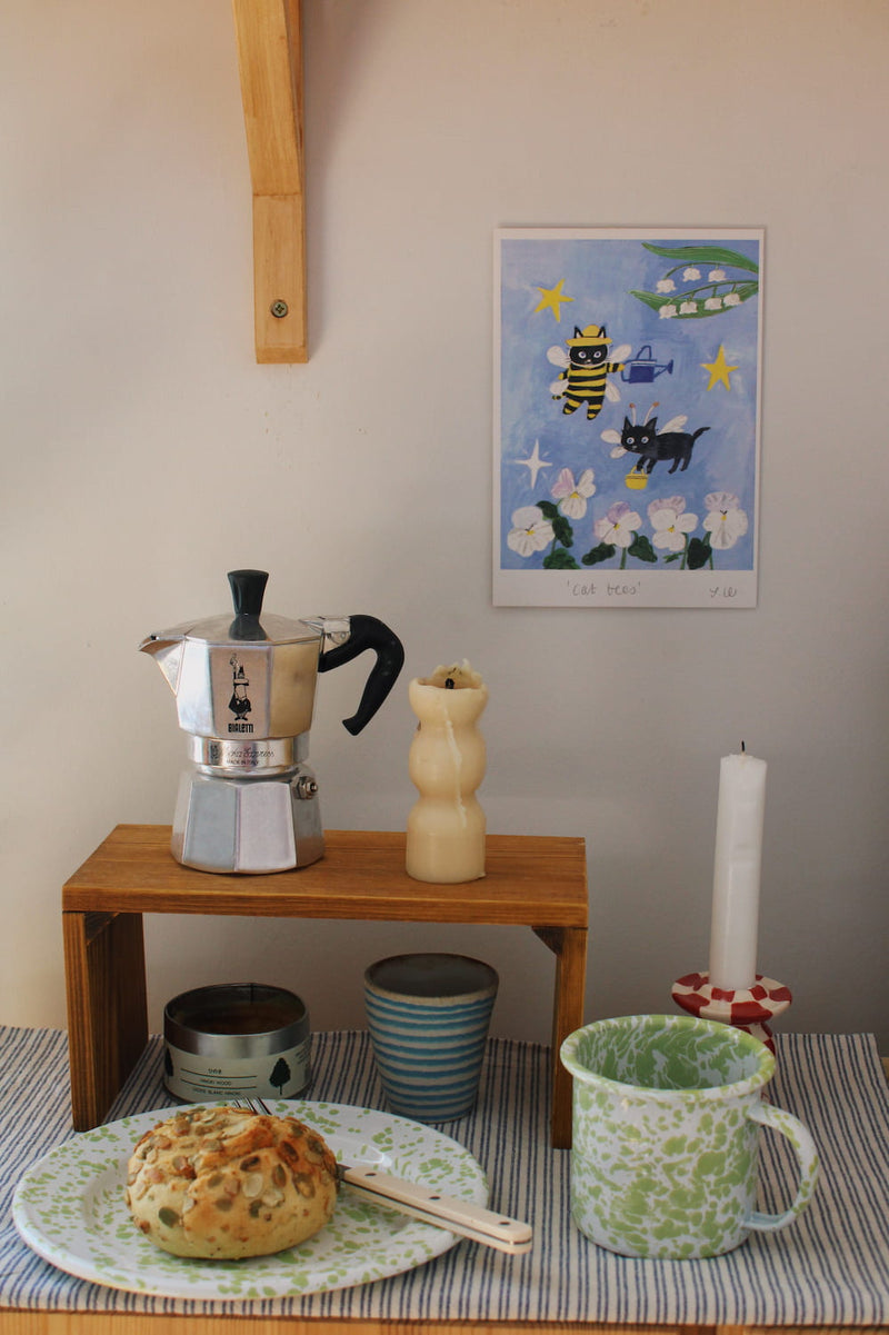 Cat Bees Art Print – illustrated art print featuring two black cats dressed as bees among flowers, styled above a coffee station with colourful ceramics and breakfast tableware