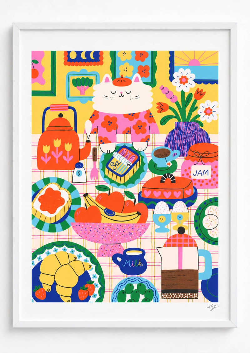 Long Breakfast Art Print- A framed art print featuring a colorful, whimsical illustration of a white cat in a pink floral dress surrounded by breakfast items like a red kettle, croissants, fruit, flowers, and coffee cups on a pink checkered tablecloth.