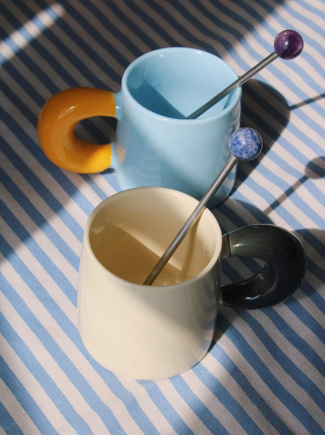 Astra drink stirrer set with ceramic cups and espresso on striped table setting.