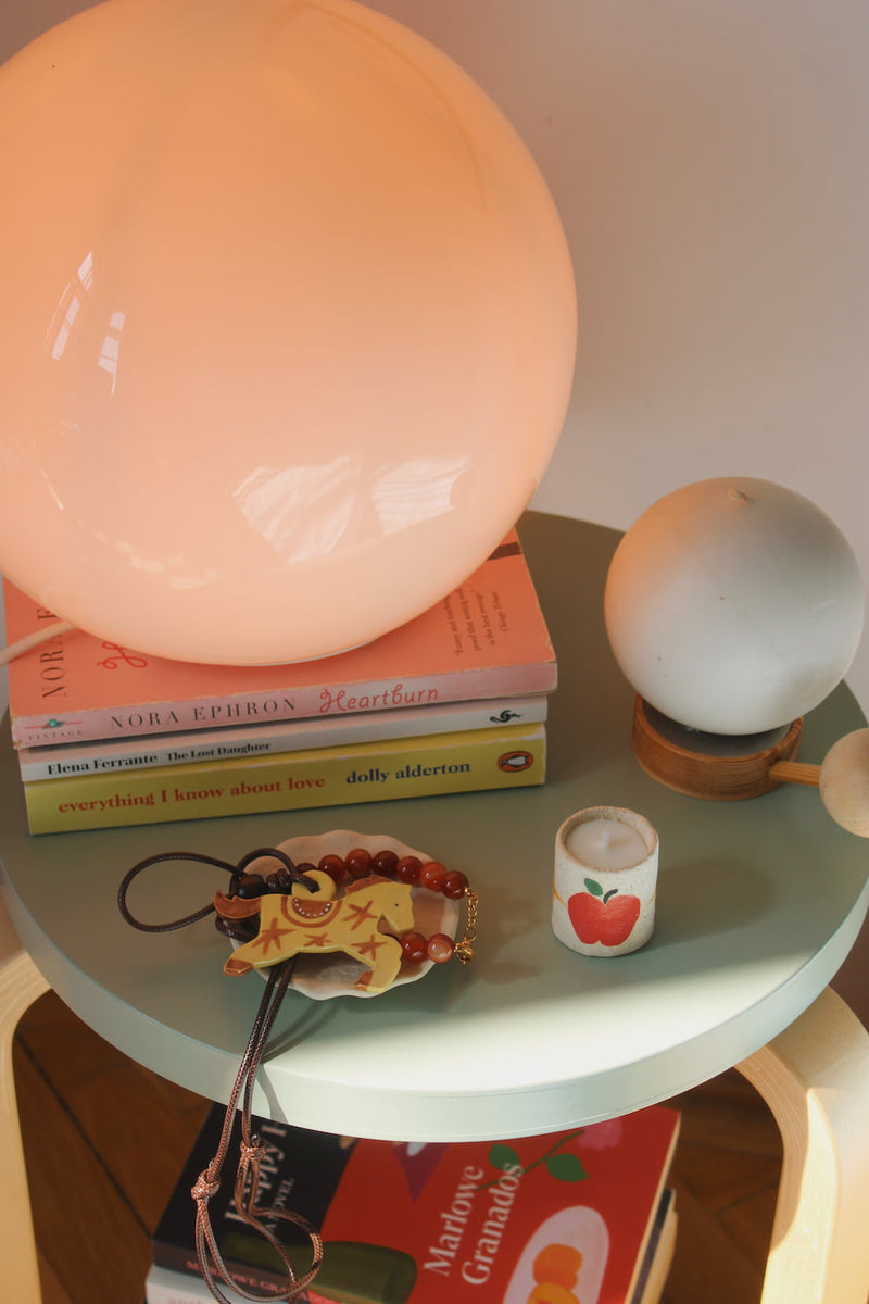 Small round table with books, a light bulb, and decorative items on a wooden floor.
