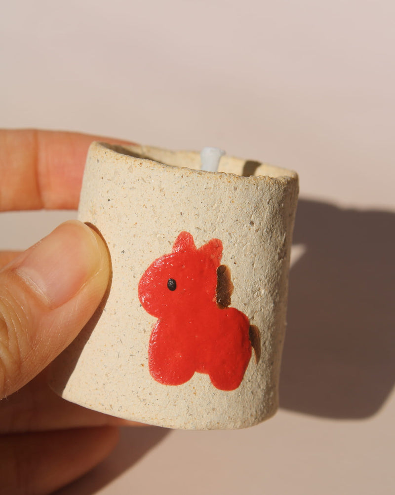 Ponino mini scented candle in handmade ceramic holder with red pony motif, cute decorative candle for cozy shelf or table styling.