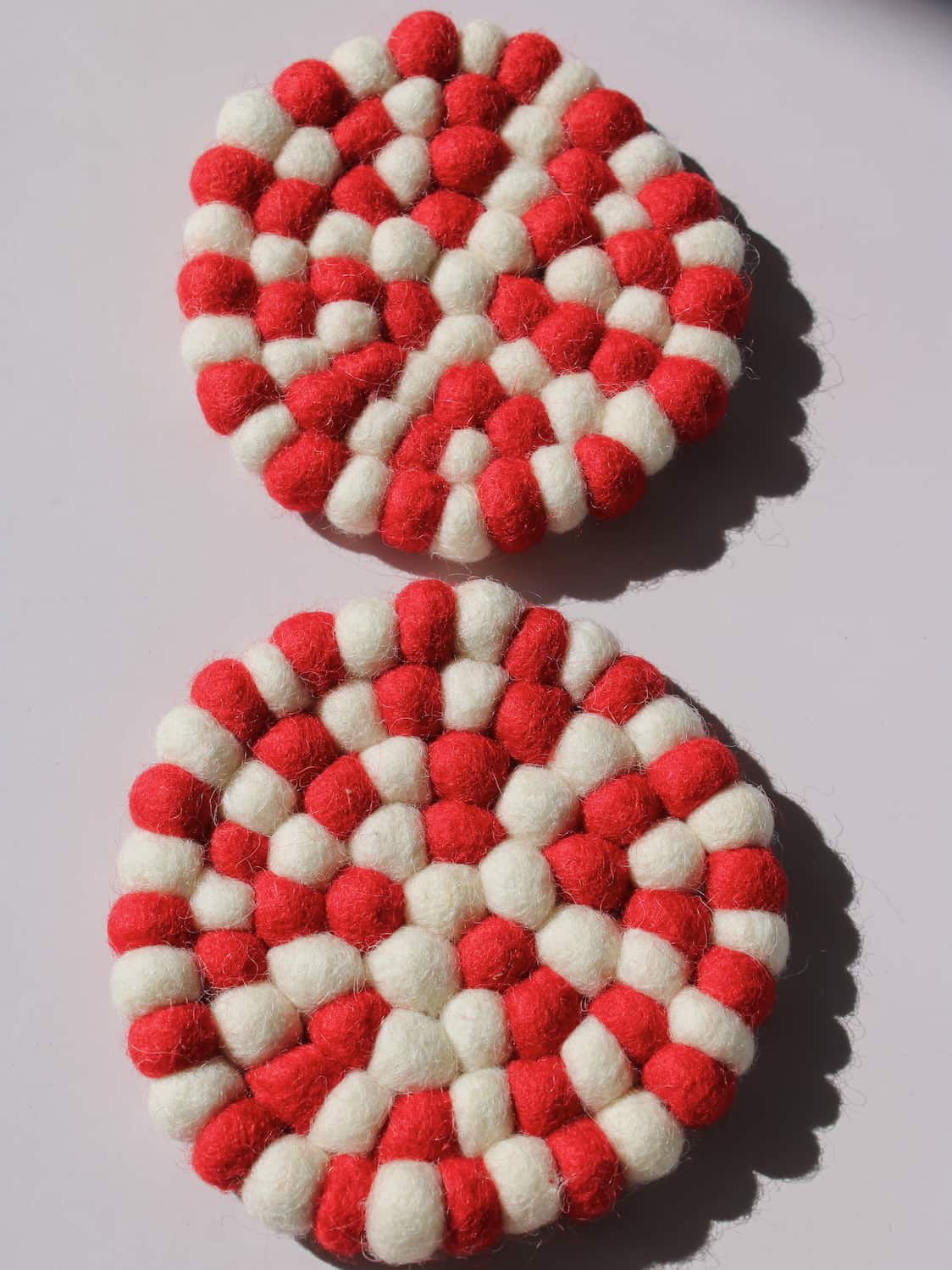 Bonbon Handmade Coaster made of red and white felted wool balls, candy-stripe pattern, top view