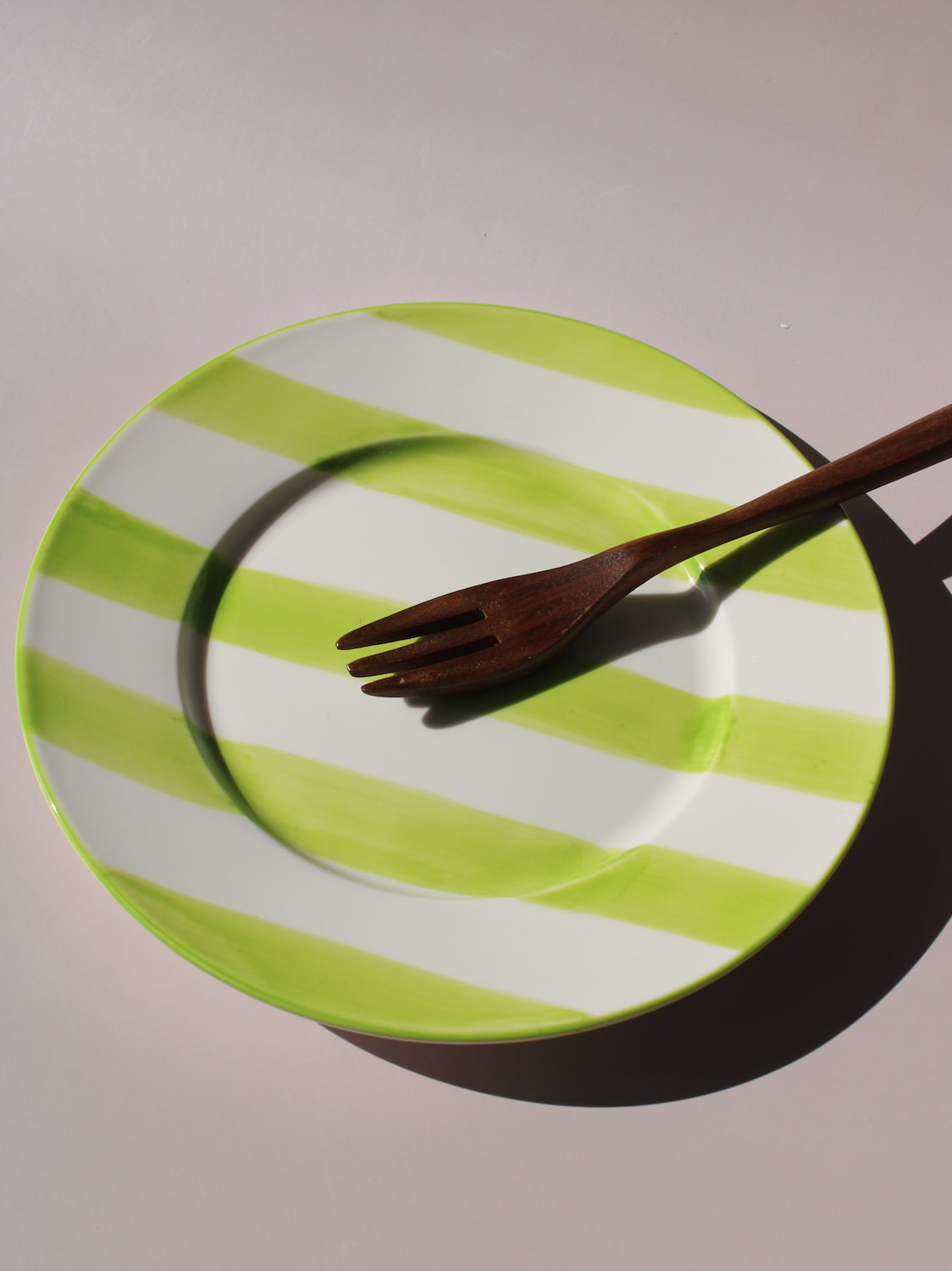 Olia Plate with bold green and white stripes, styled with a wooden fork, handmade ceramic plate top view