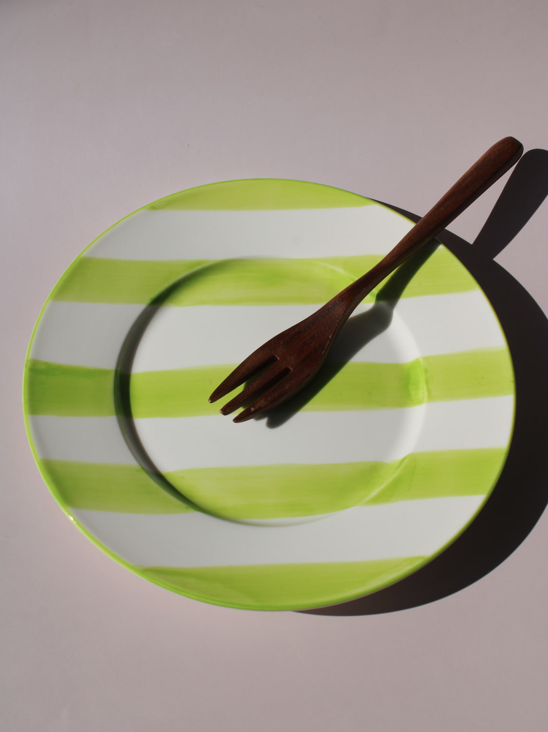 Olia Plate with bold green and white stripes, styled with a wooden fork, handmade ceramic plate top view