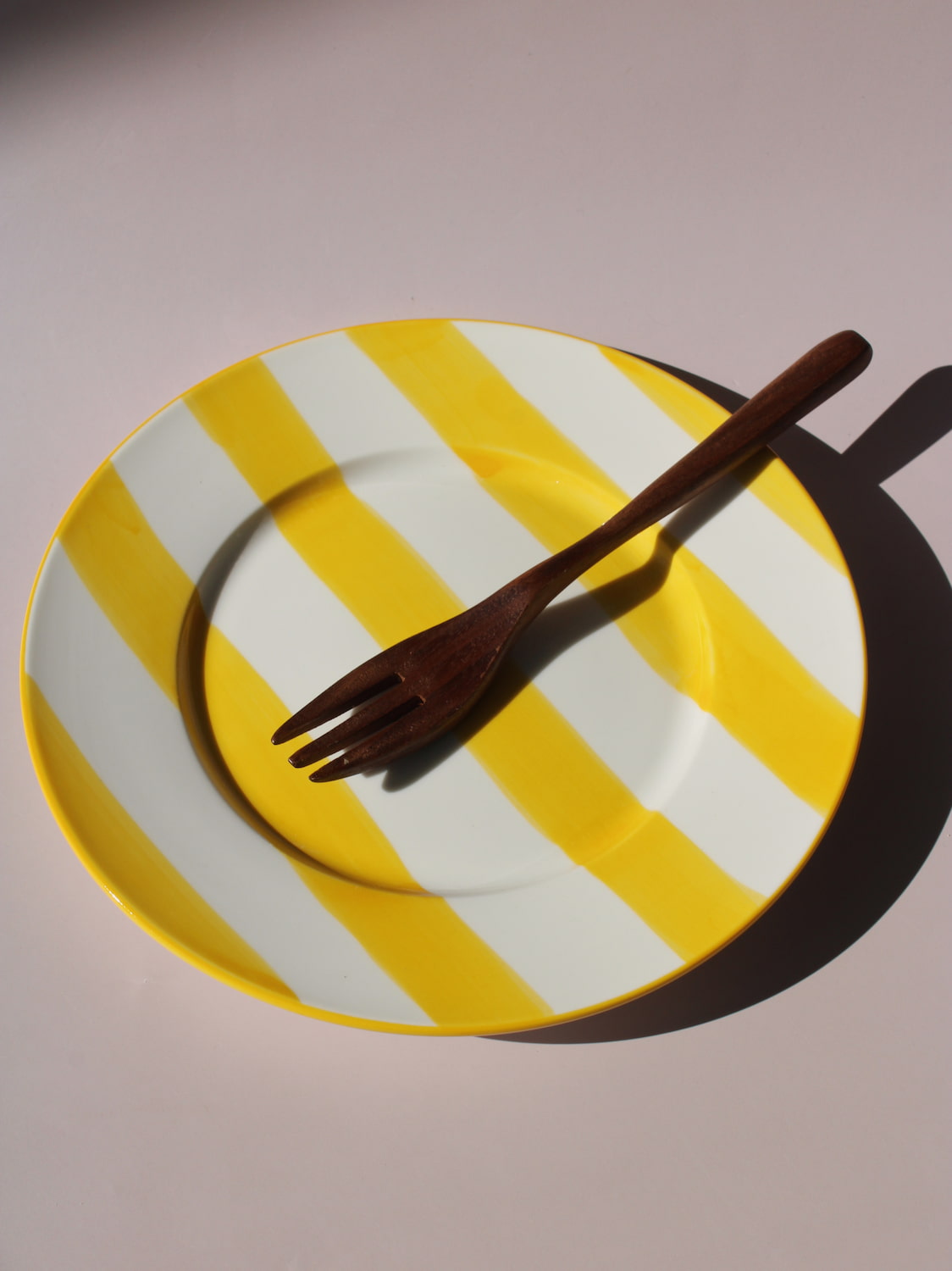 Etta Plate with bold yellow and white stripes, styled with a wooden fork, handmade ceramic plate top view