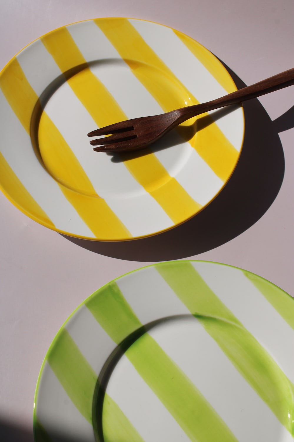 Etta Plate with bold yellow and white stripes, styled with a wooden fork, handmade ceramic plate top view