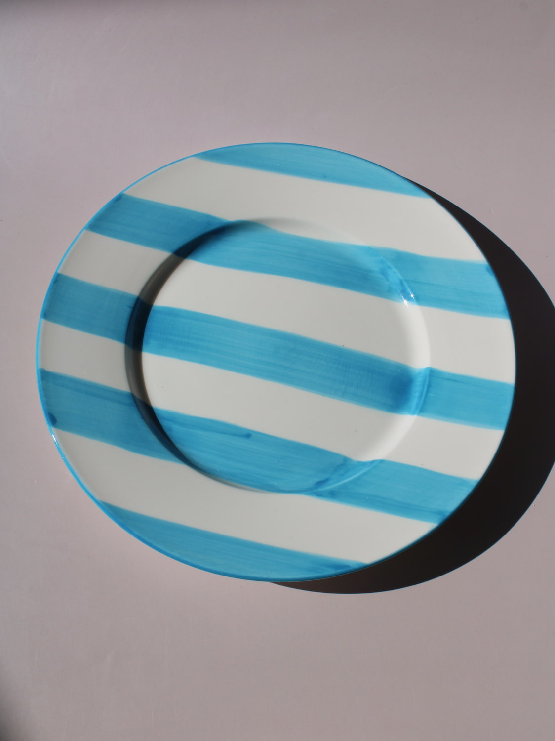 White ceramic plate with hand-painted turquoise blue stripes, Mirel Plate by Mimo Collective, top down view