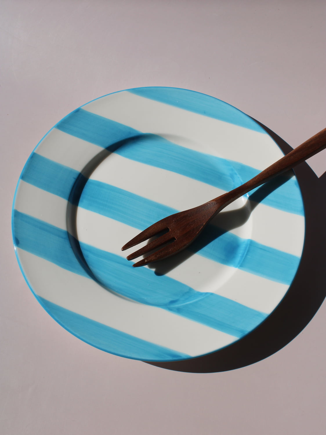 White ceramic plate with hand-painted turquoise blue stripes, Mirel Plate by Mimo Collective, top down view