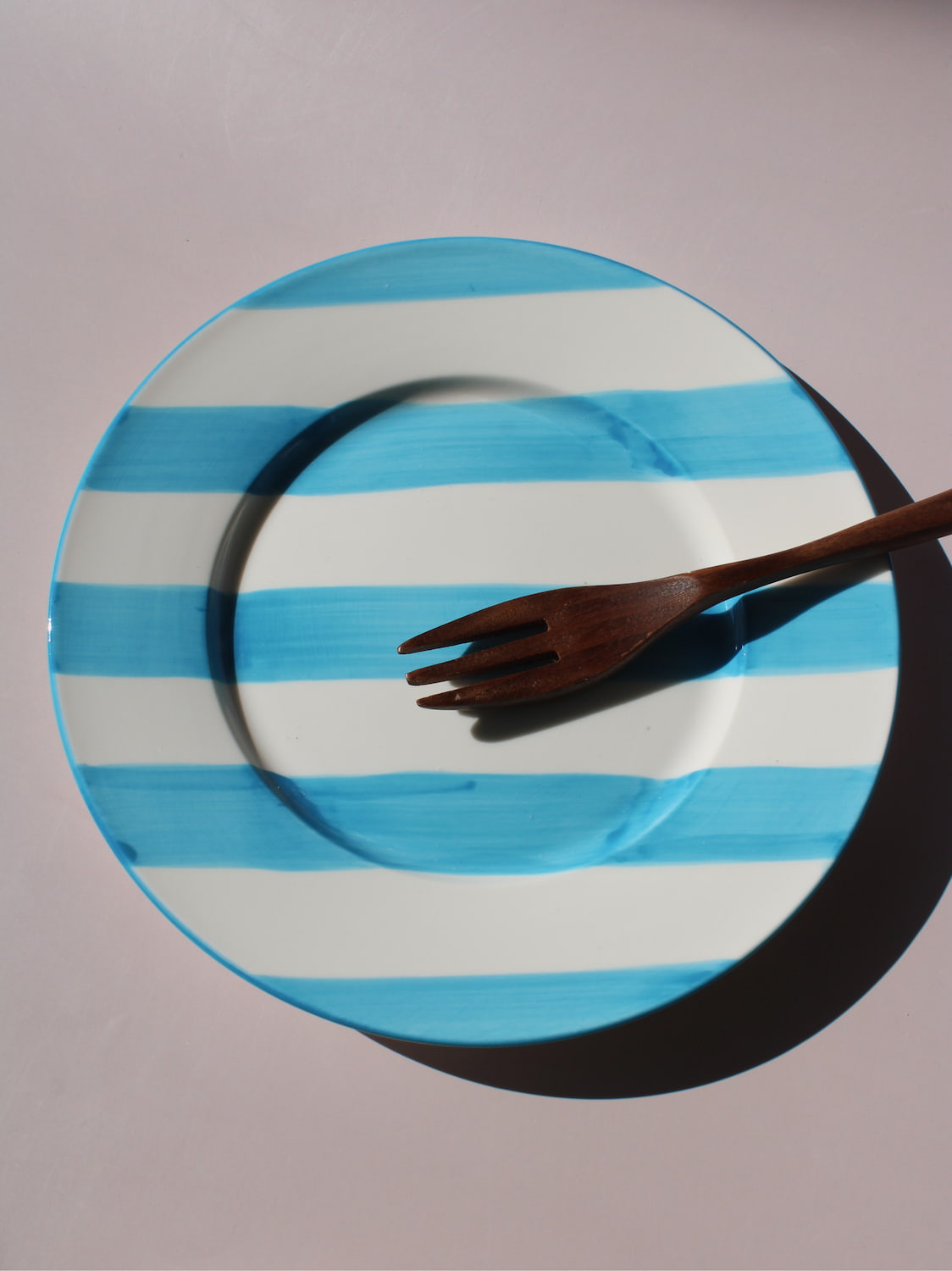 White ceramic plate with hand-painted turquoise blue stripes, Mirel Plate by Mimo Collective, top down view