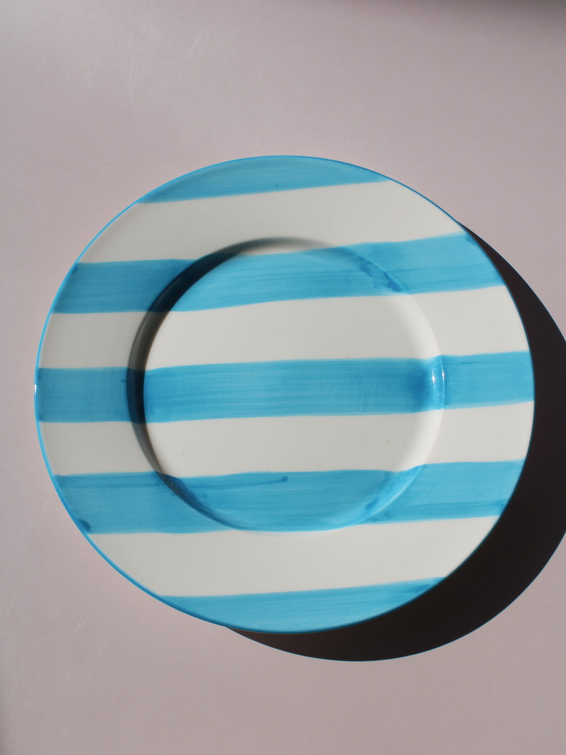 White ceramic plate with hand-painted turquoise blue stripes, Mirel Plate by Mimo Collective, top down view