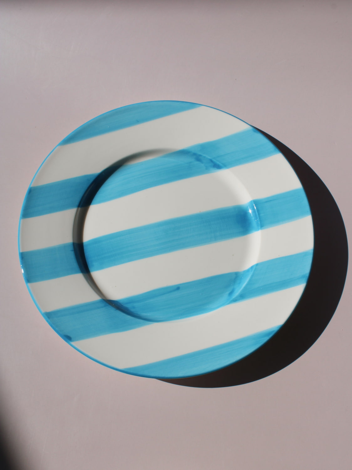 White ceramic plate with hand-painted turquoise blue stripes, Mirel Plate by Mimo Collective, top down view