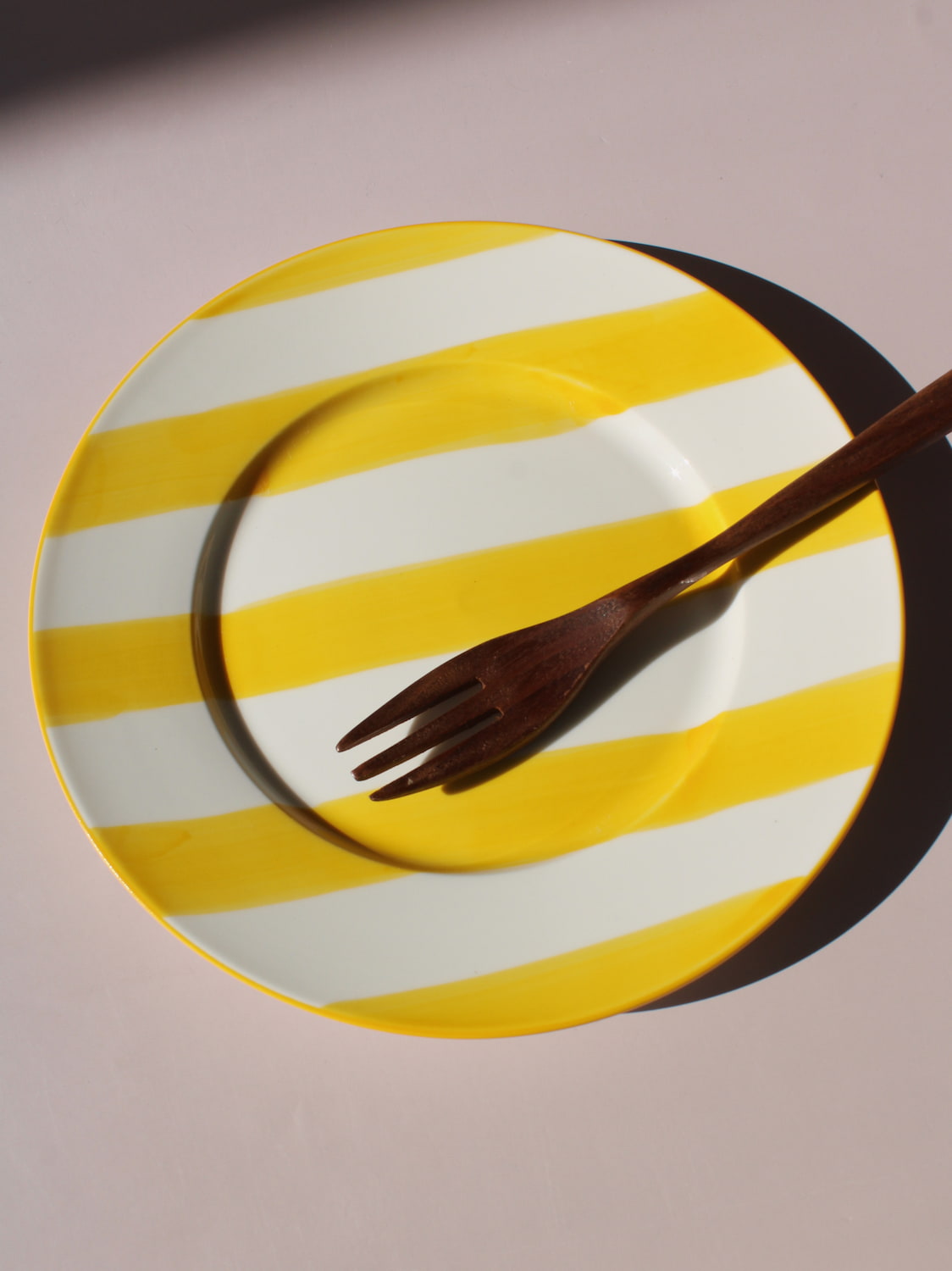 Etta Plate with bold yellow and white stripes, styled with a wooden fork, handmade ceramic plate top view