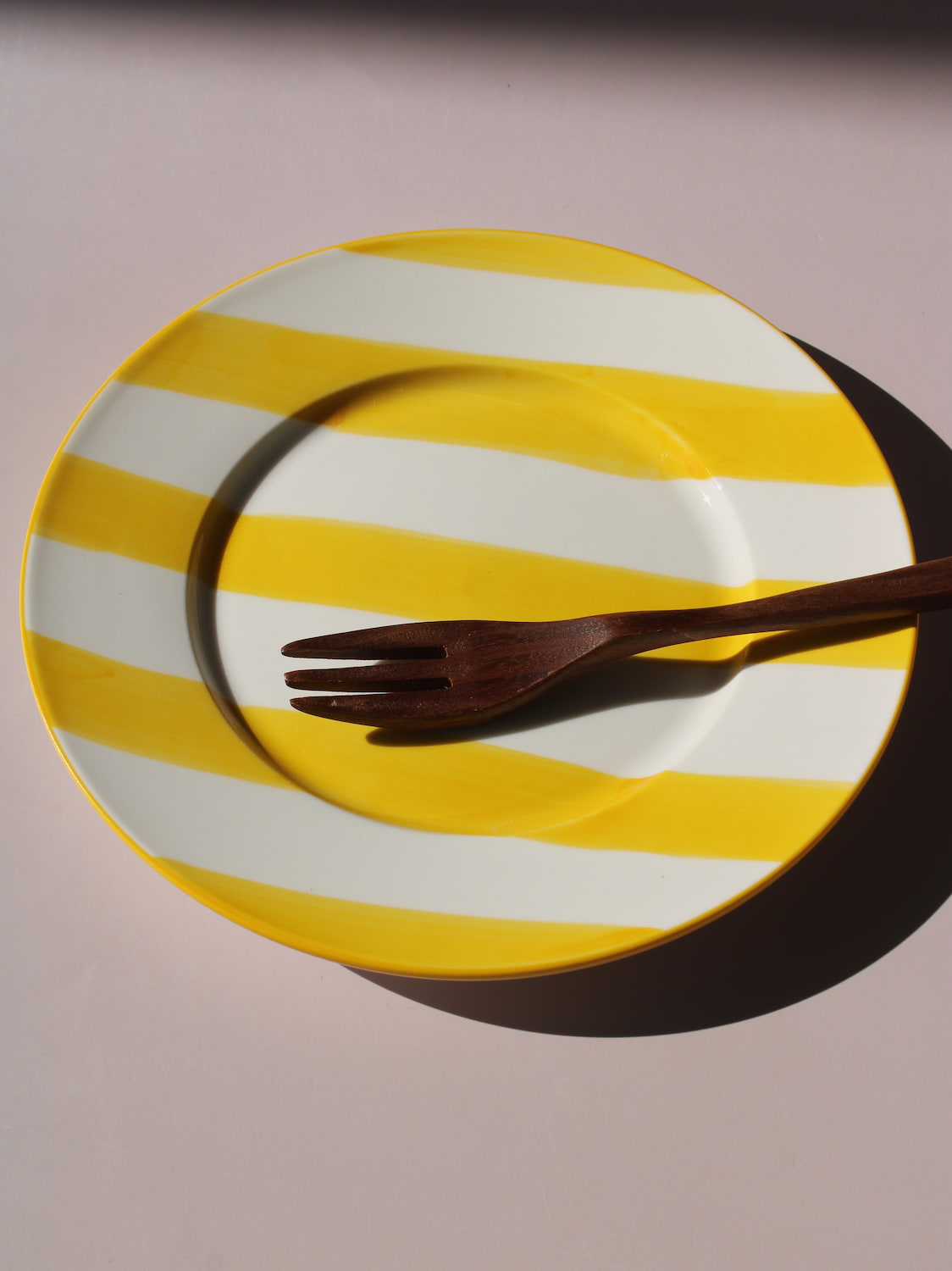 Etta Plate with bold yellow and white stripes, styled with a wooden fork, handmade ceramic plate top view