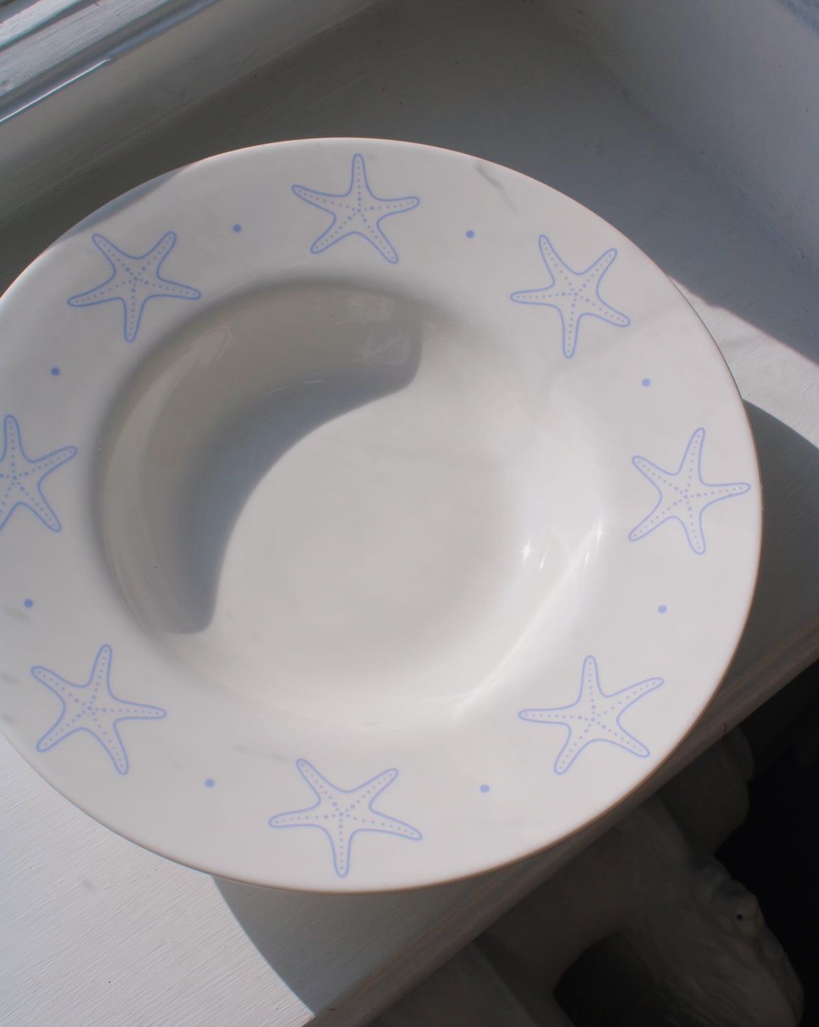 Astrella ceramic plate with blue starfish motif, coastal inspired tableware for seafood, pasta, or everyday dining.
