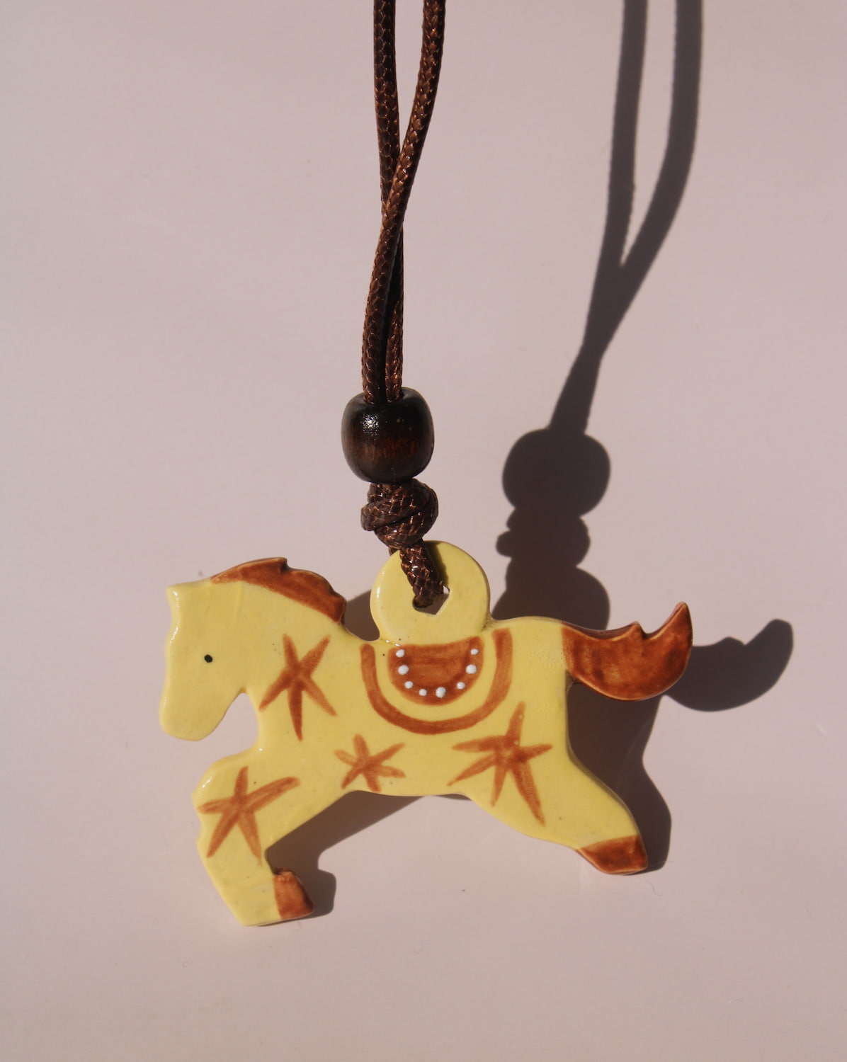 Amber pony charm necklace with yellow handmade ceramic horse pendant on adjustable cord.