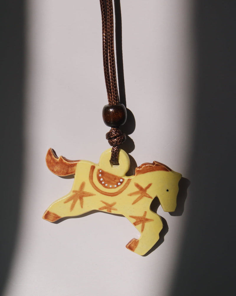 Amber pony charm necklace with yellow handmade ceramic horse pendant on adjustable cord.