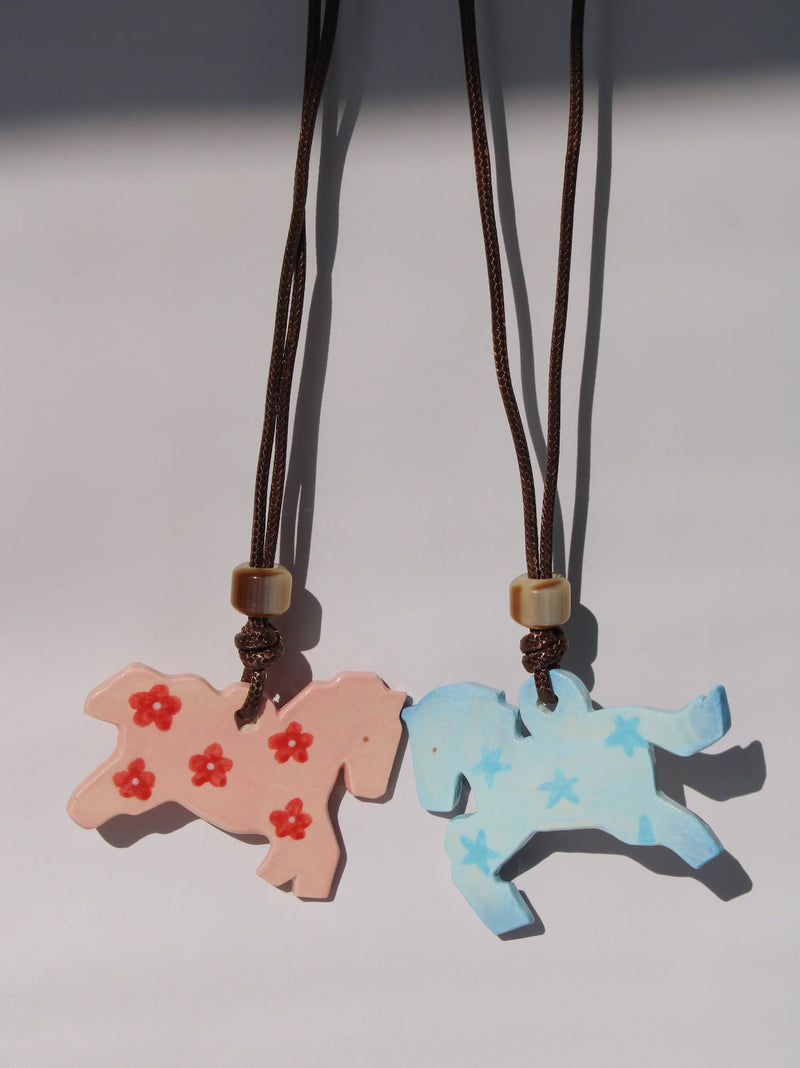 Petal Pony and Stardust Pony Charm Necklaces side by side, pink floral and blue starry ceramic horse pendants