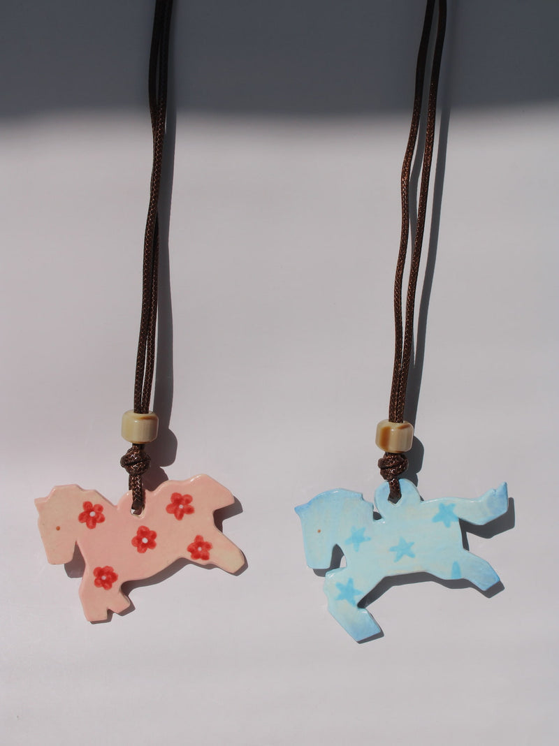 Petal Pony and Stardust Pony Charm Necklaces side by side, pink floral and blue starry ceramic horse pendants
