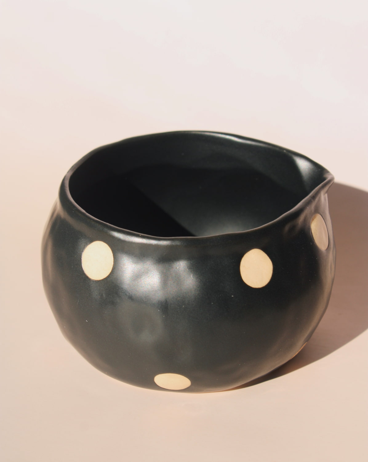 Black polka dot ceramic pouring matcha bowl with spout, modern speckled kitchen serveware.