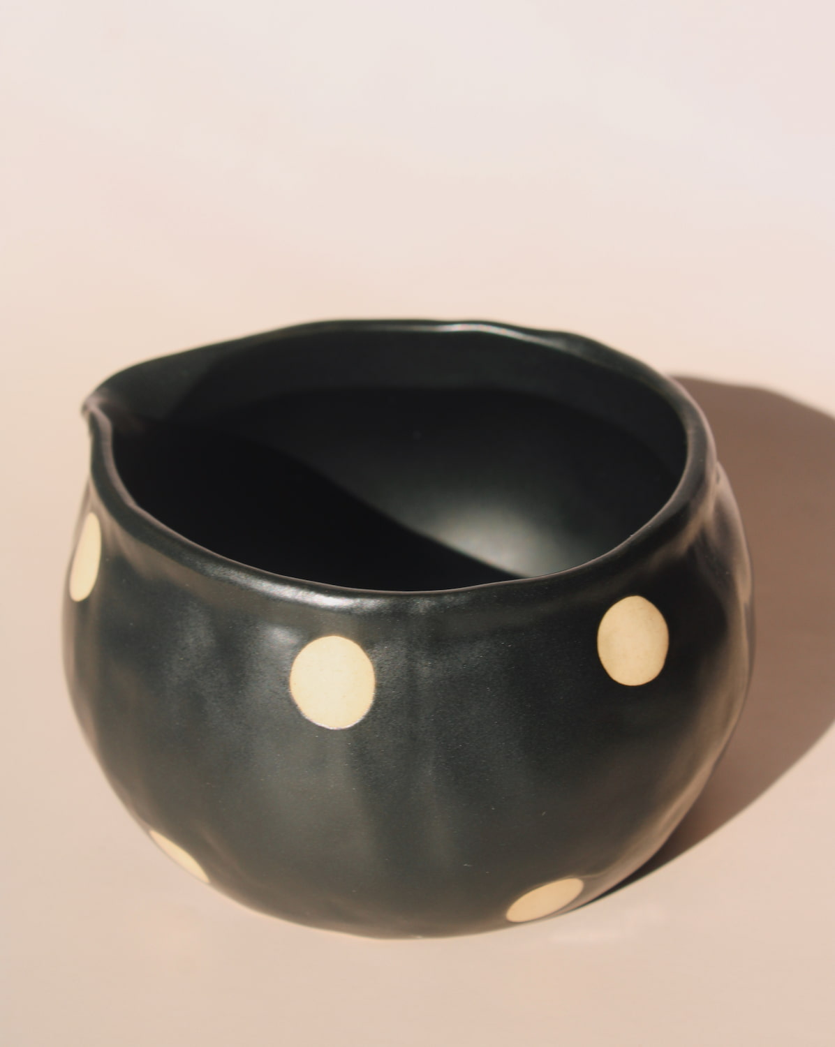 Black polka dot ceramic pouring matcha bowl with spout, modern speckled kitchen serveware.