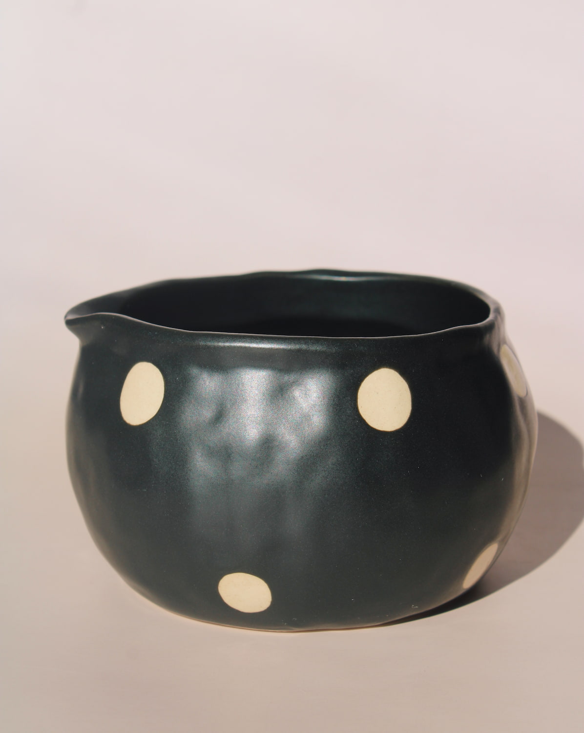Black polka dot ceramic pouring matcha bowl with spout, modern speckled kitchen serveware.