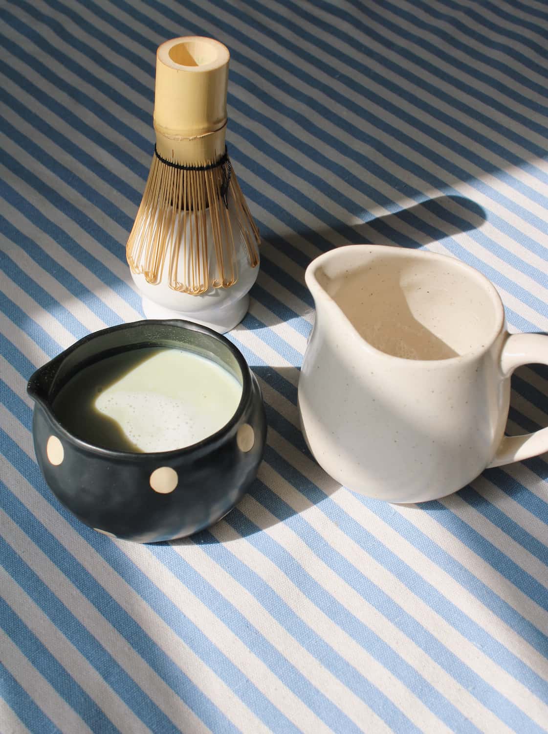 Mochi matcha bowl with deep glaze styled with bamboo whisk and ceramic pitcher