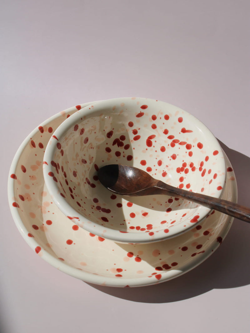 Bera Ceramic Bowl and Plate in cream with red speckled dot pattern, on a soft pink background.
