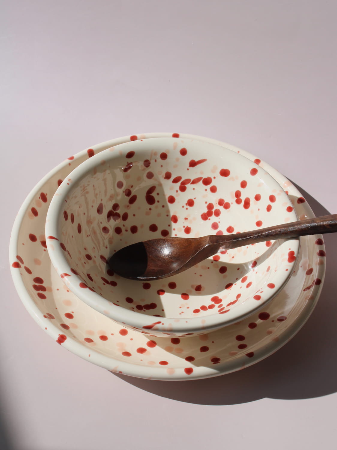 Bera Ceramic Bowl and Plate in cream with red speckled dot pattern, on a soft pink background.