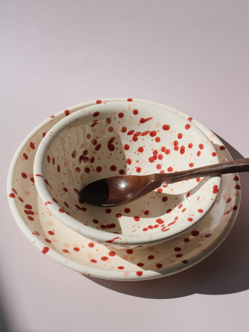 Bera Ceramic Bowl and Plate in cream with red speckled dot pattern, on a soft pink background.