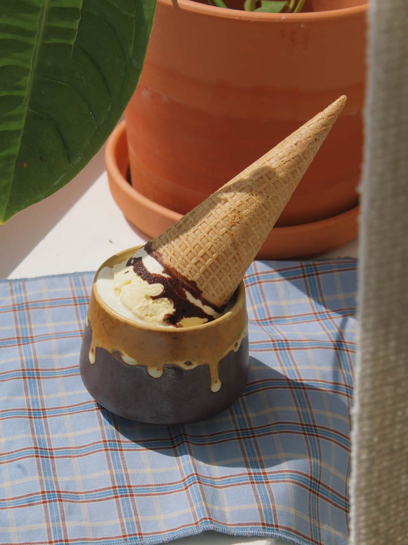 Oro ceramic cup in amber and charcoal glaze, styled with vanilla ice cream, chocolate drizzle and a waffle cone