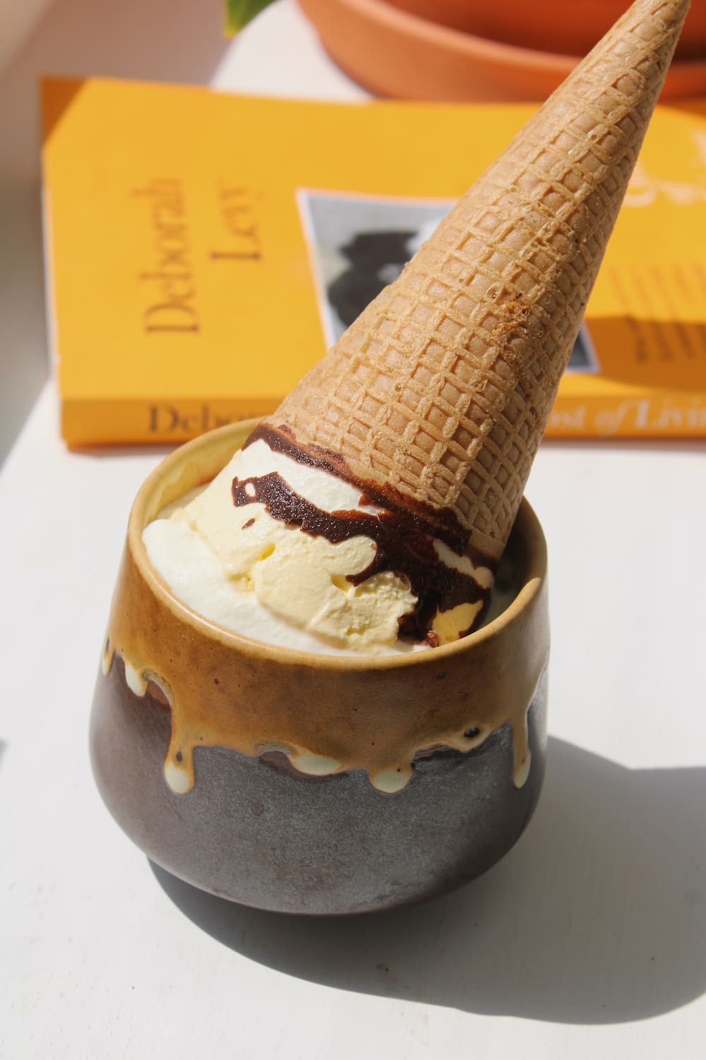 Oro ceramic cup in amber and charcoal glaze, styled with vanilla ice cream, chocolate drizzle and a waffle cone
