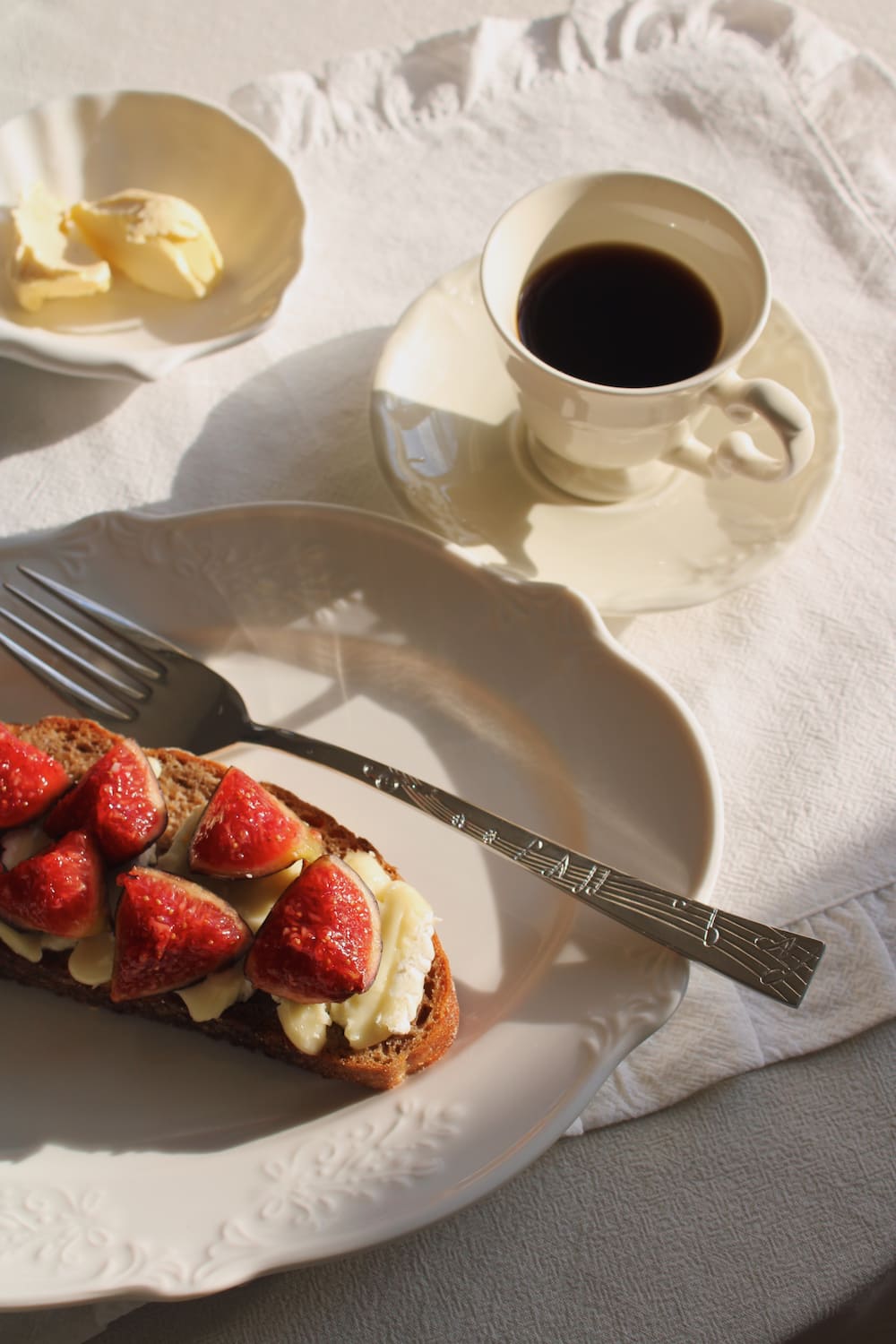 Plate of strawberry toast with a cup of coffee on a white tablecloth