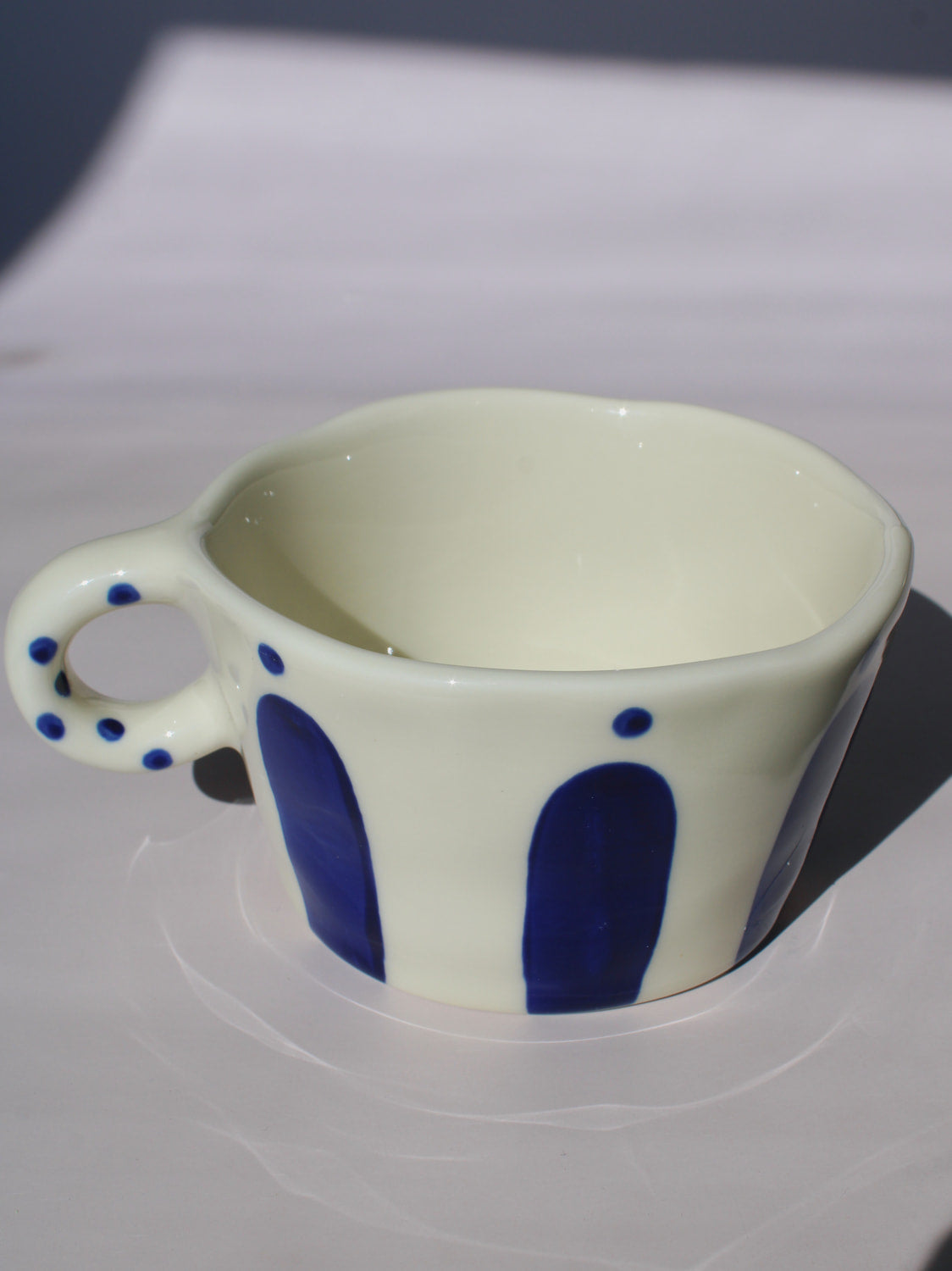 Enzo Ceramic Mug with bold blue arch stripes and polka dot handle on cream base, handmade pottery coffee mug