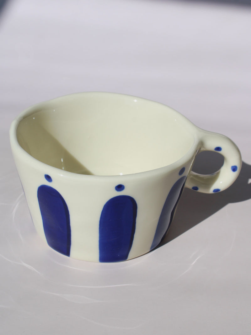 Enzo Ceramic Mug with bold blue arch stripes and polka dot handle on cream base, handmade pottery coffee mug