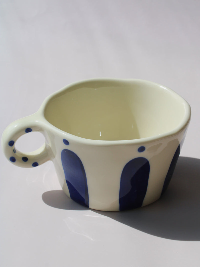 Enzo Ceramic Mug with bold blue arch stripes and polka dot handle on cream base, handmade pottery coffee mug